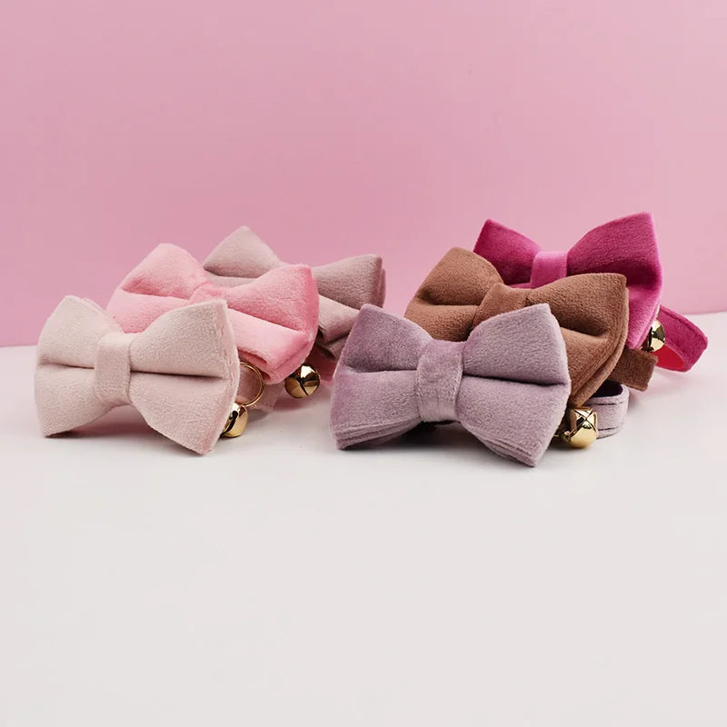 A collection of velvet cat collars in shades of pink, mauve, and brown with gold-colored hardware.
