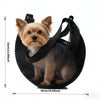 A small, light brown dog is sitting inside a black mesh pet carrier sling.