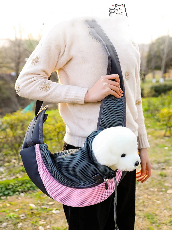 A person is holding a black and pink breathable pet carrier backpack outdoors.