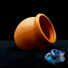 An orange clay aquarium cave decoration with a wide opening sits on a dark surface.