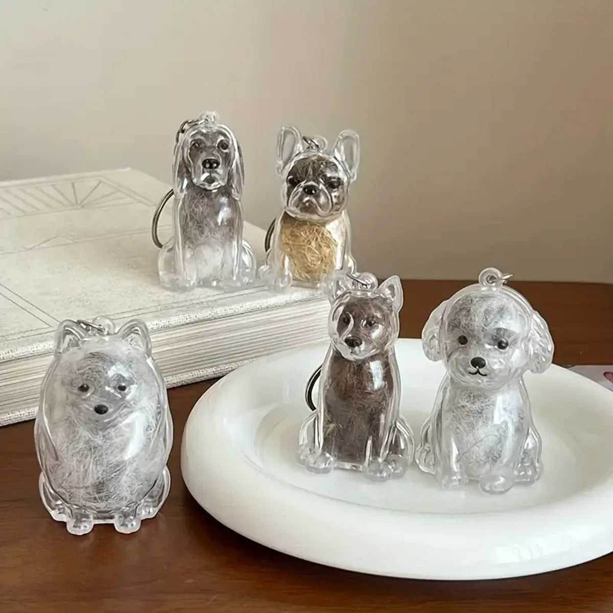 A collection of clear glass pet hair storage keychains featuring various dog breeds sitting on a white plate.