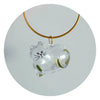 A clear glass heart shaped charm with a cat face and green hair inside, suspended from a gold-colored cord.