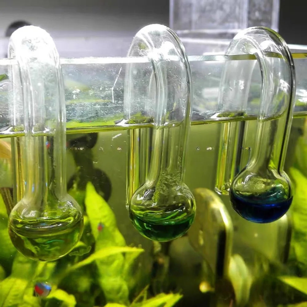 A glass drop checker for an aquarium, showing a green liquid solution.