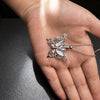 Silver butterfly ashes urn necklace worn on a person's hand.