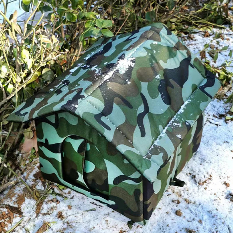 Abri pour chat extérieur vert camouflage et imperméable, posé au sol avec de la neige à proximité.