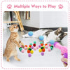 A tabby cat plays with colorful plush balls and a pink launcher toy.