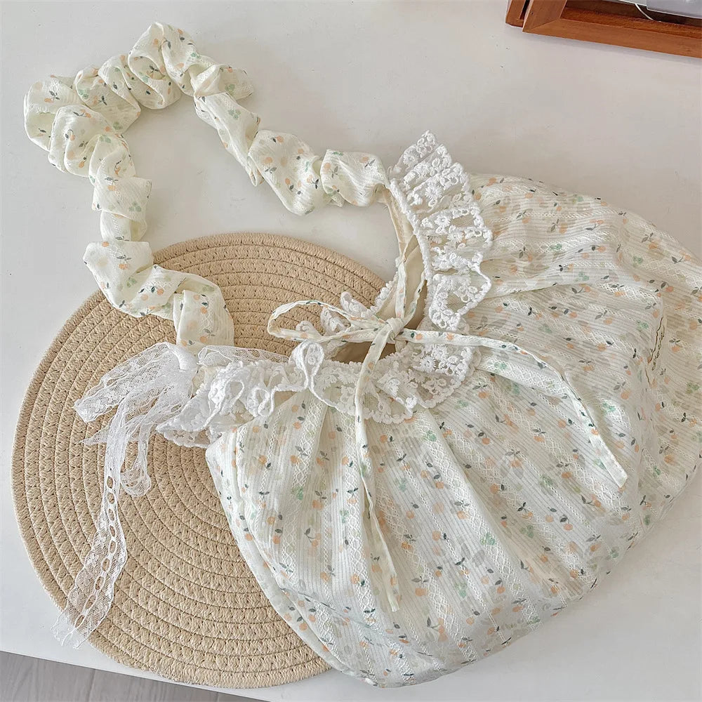 A cream floral lace bowknot shoulder bag with pleated fabric resting on a woven straw mat.