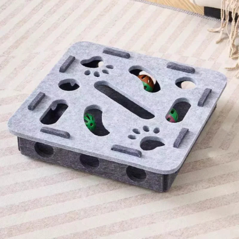 A gray felt maze puzzle toy for cats featuring various holes and a bell ball.