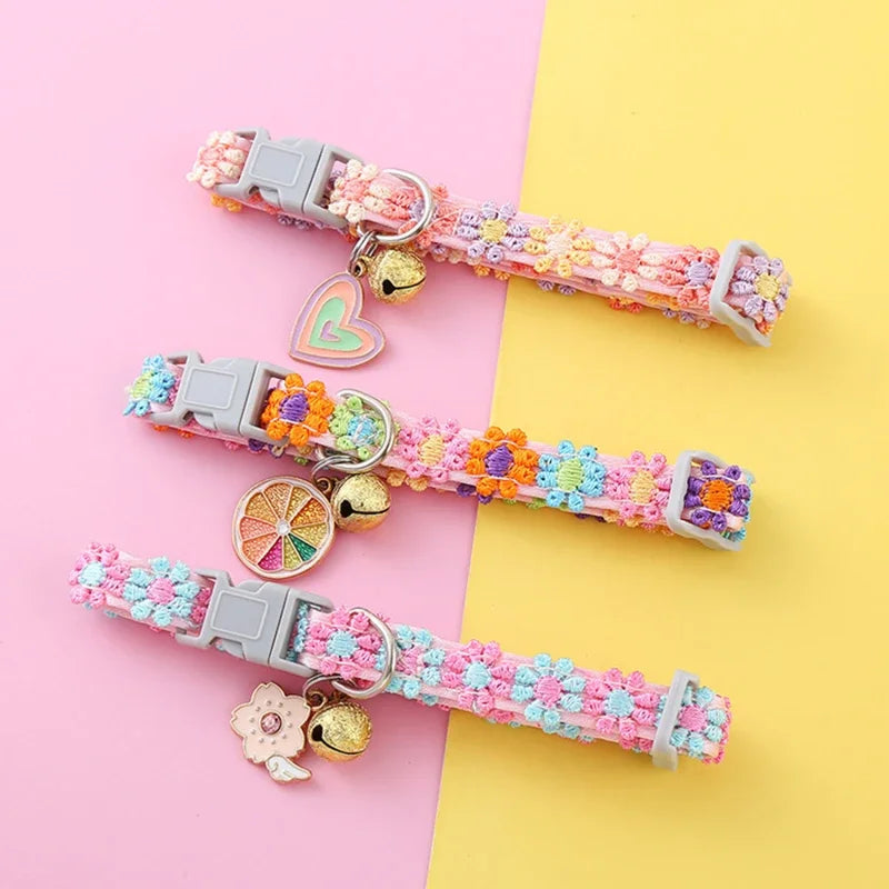 Pink and purple embroidered safety cat collar with a bell displayed on a light pink and yellow background.