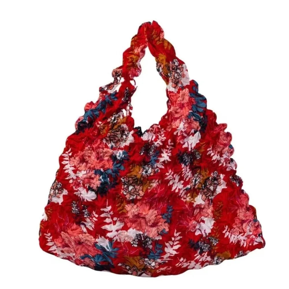 A vibrant red floral fabric tote bag with multicolored leaves and flowers.