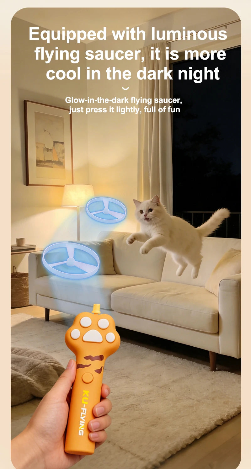 An orange interactive cat wand toy with a luminous flying saucer attachment is being held by a hand on a light-colored sofa.