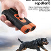 Eine Hand hält ein schwarzes Ultraschall-Hundabwehrmittel, mit einem Hund im Hintergrund, der rennt.