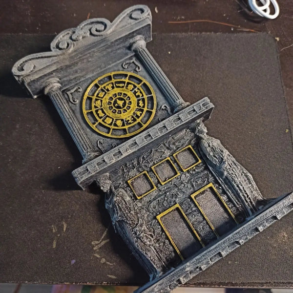 A 3D printed clock tower dial prop featuring an ornate golden circular design on a gray stone structure.