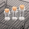 Ten mini glass bottles with cork stoppers resting on a black wire grill.