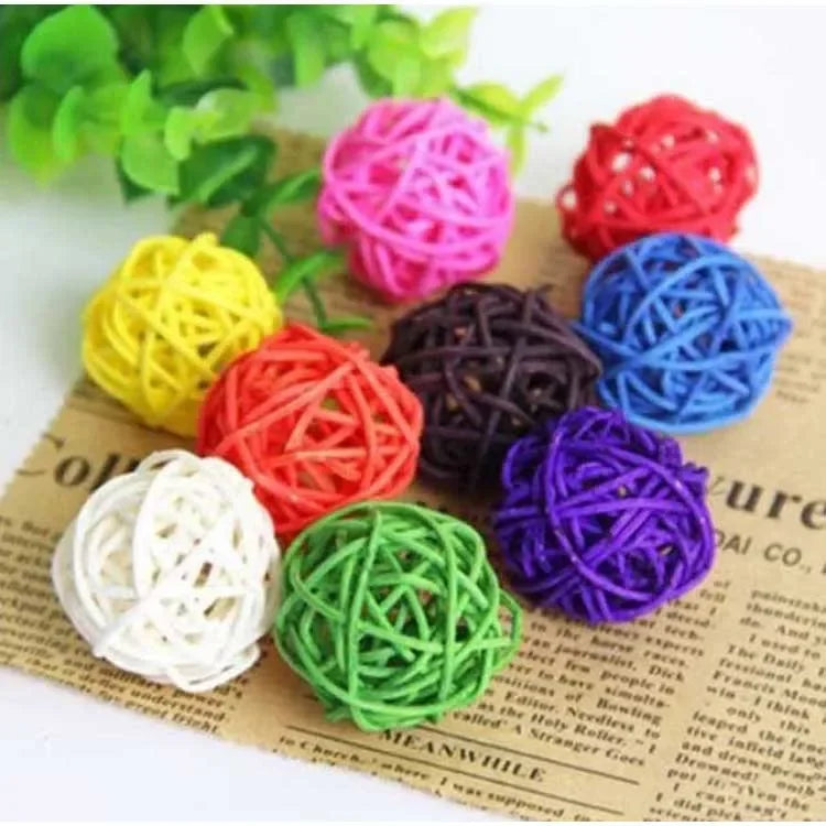 A collection of colorful natural rattan chewing balls for parrots in various shades including yellow, pink, red, purple, and 