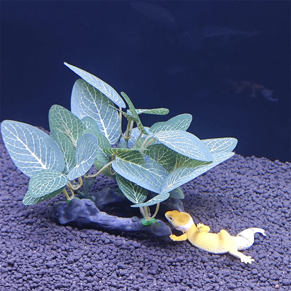 A small green plant with large leaves is growing from a dark tree trunk decoration on black gravel.