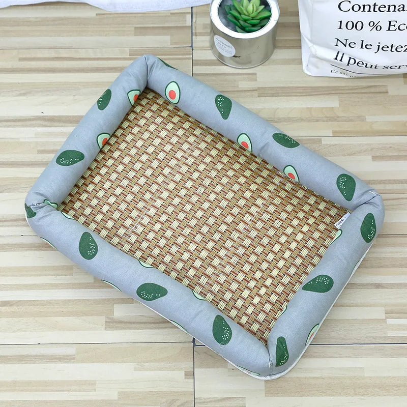 A gray pet bed with a woven mat and avocado-shaped accents is shown on a wooden floor.