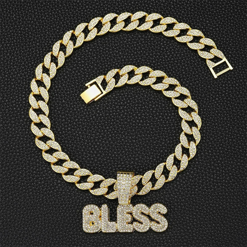 A gold iced out letter and animal pendant Cuban link chain necklace displayed against a black background.