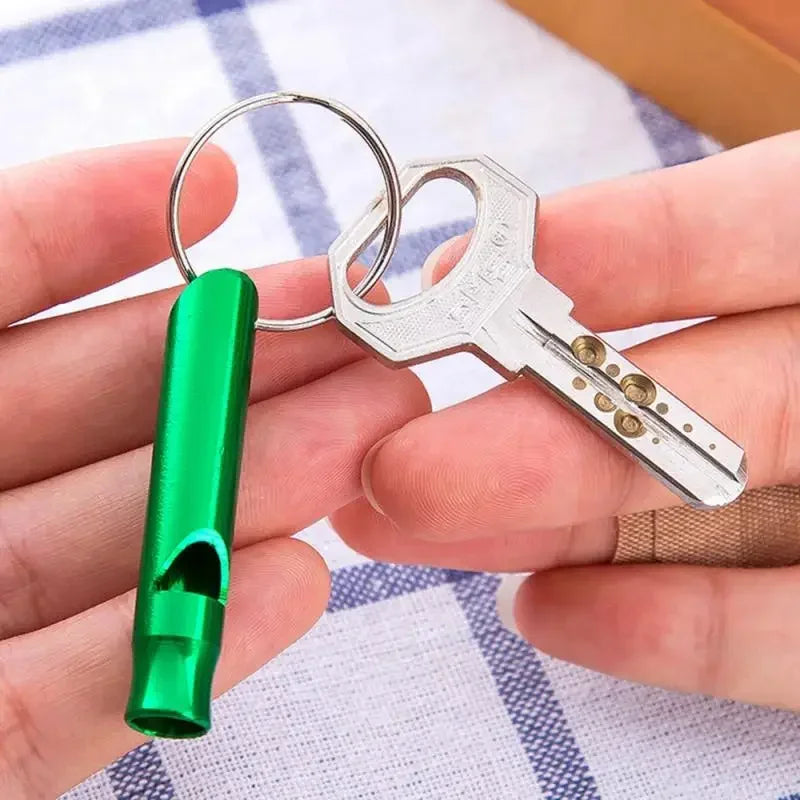 Edelstahl-Hundetrainingspfeife an einem grünen Lanyard in der Hand einer Person gehalten.