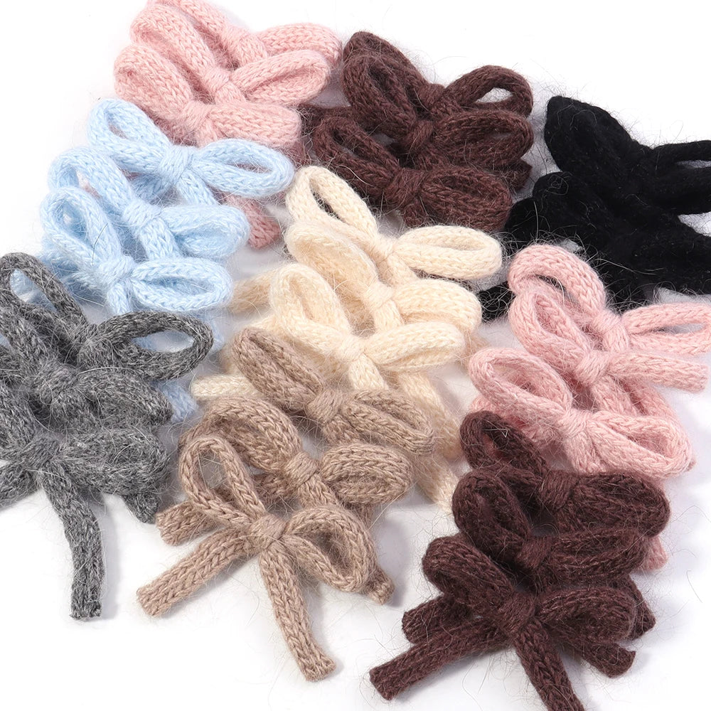 A set of six handmade knitted cotton bows in various shades including pink, blue, gray, brown, and black.