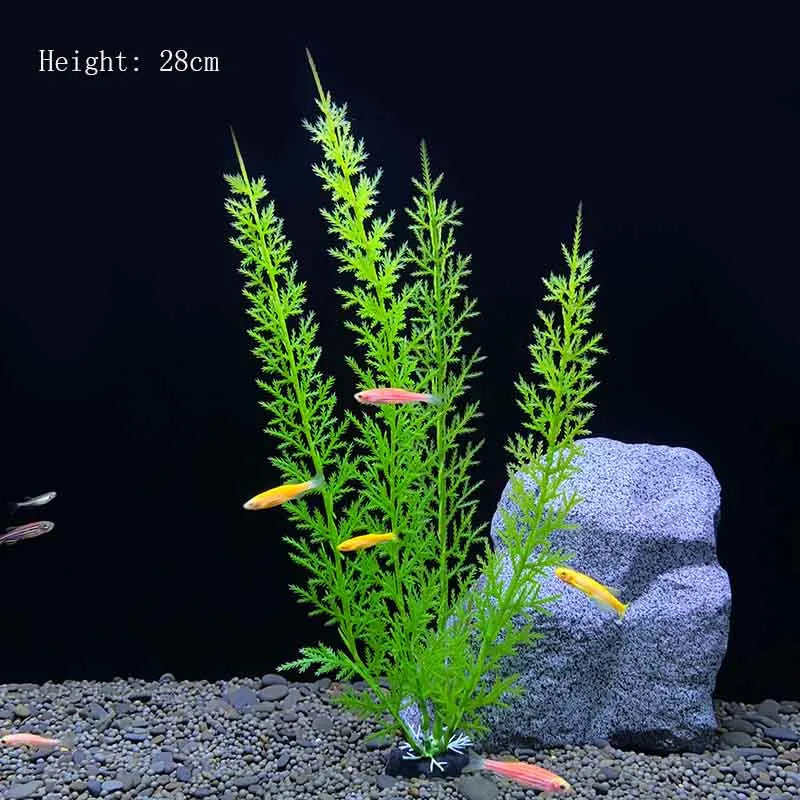 A tall artificial aquarium plant with bright green foliage and small orange fish is displayed on a dark gravel surface next t