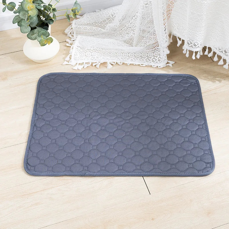Tapis de dressage pour chien gris lavable à motif hexagonal, posé sur un plancher en bois clair à côté d'un tissu en dentelle