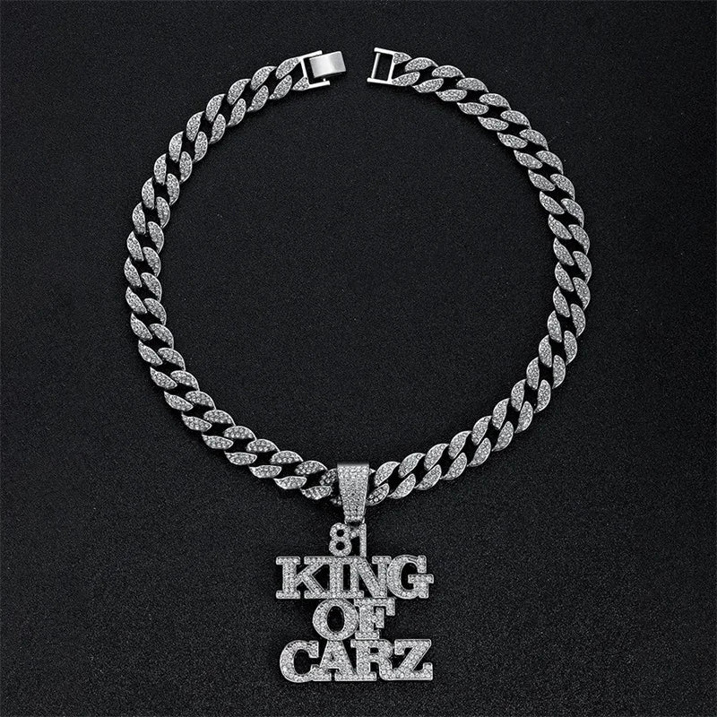 A silver iced out letter and animal pendant Cuban link chain necklace displayed against a black background.