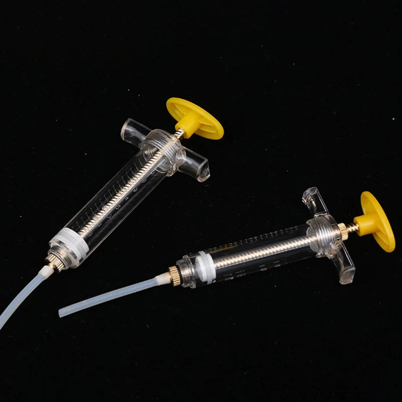 A clear plastic syringe with a yellow plunger and soft hose is shown against a black background.