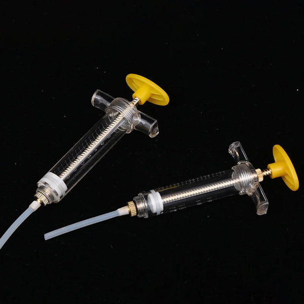 A clear plastic syringe with a yellow plunger and soft hose is shown against a black background.