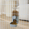 A clear automatic pet feeder containing dry kibble is visible through a wire mesh barrier.