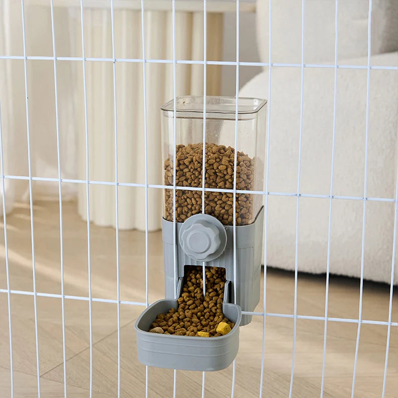 A clear automatic pet feeder containing dry kibble is visible through a wire mesh barrier.