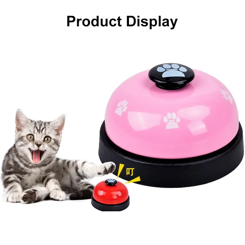 A pink and black pet training bell with a paw print design is shown next to a kitten.