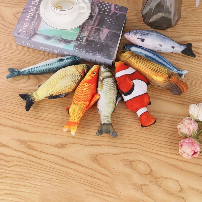 A collection of colorful plush fish toys and a book are displayed on a wooden surface.