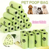 A stack of green pet poop bags and several individual rolls are shown with various dog breeds in the background.