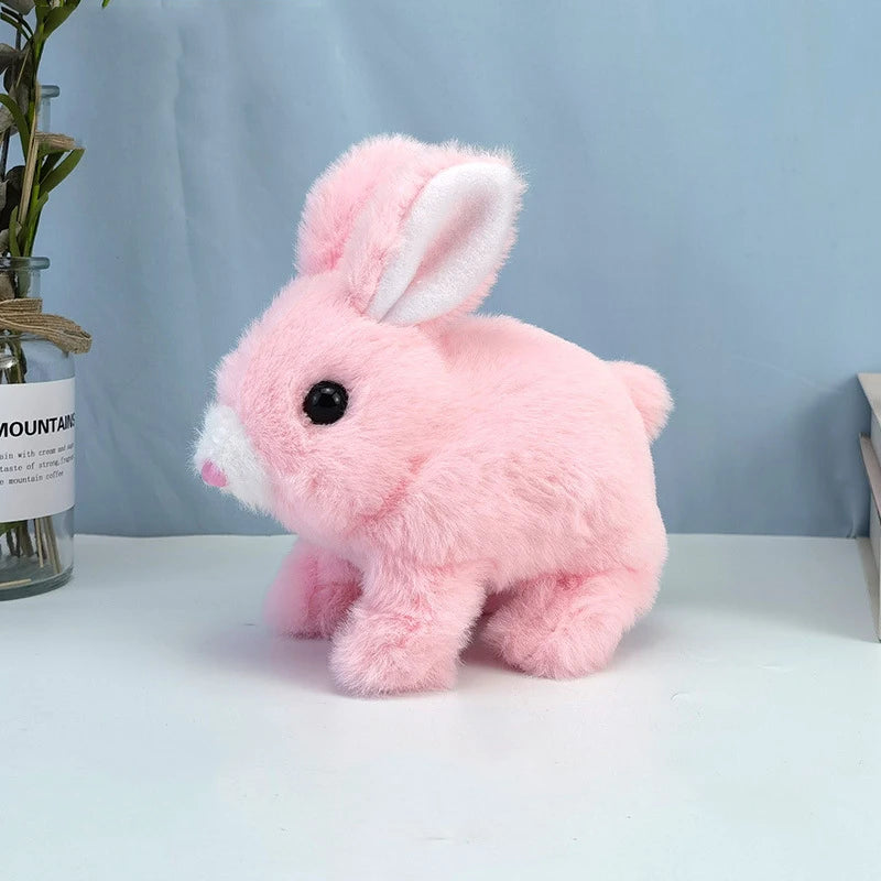 A pink plush bunny with white inner ears sitting on a white surface.