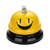 A yellow classic brass call bell with a smiling face and a black base.