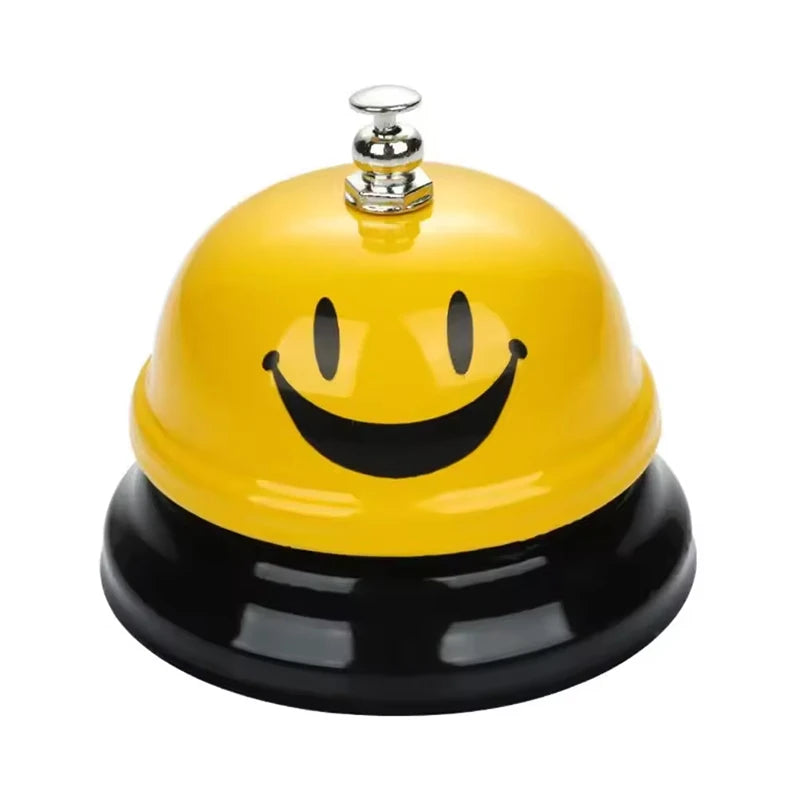 A yellow classic brass call bell with a smiling face and a black base.