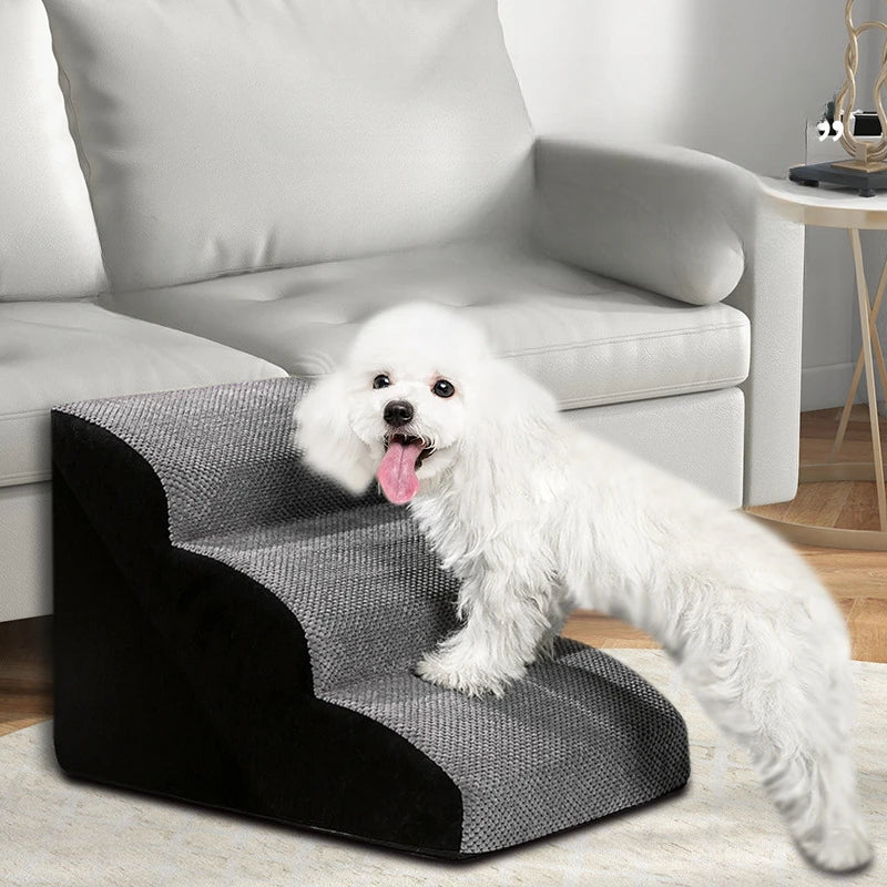 A fluffy white dog is standing on a black and gray memory foam pet ramp in a living room setting.