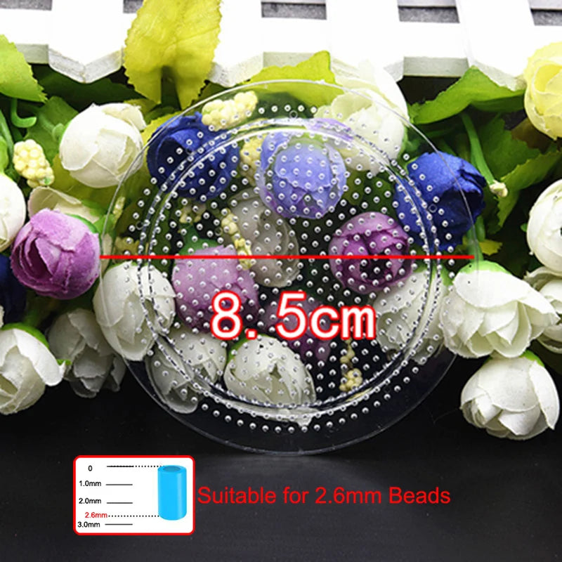 A clear petri dish filled with white and purple flowers and small beads, demonstrating a 8.5cm measurement for 2.6mm beads.