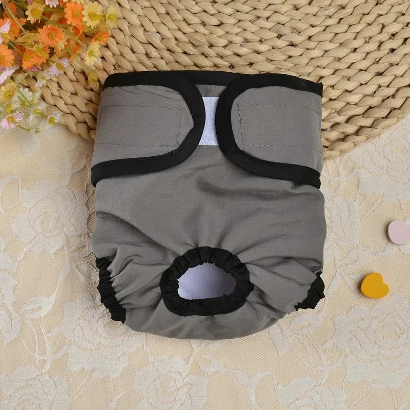 Couches réutilisables pour chien grises avec bordure noire et ajustement réglable sur un tapis tissé.