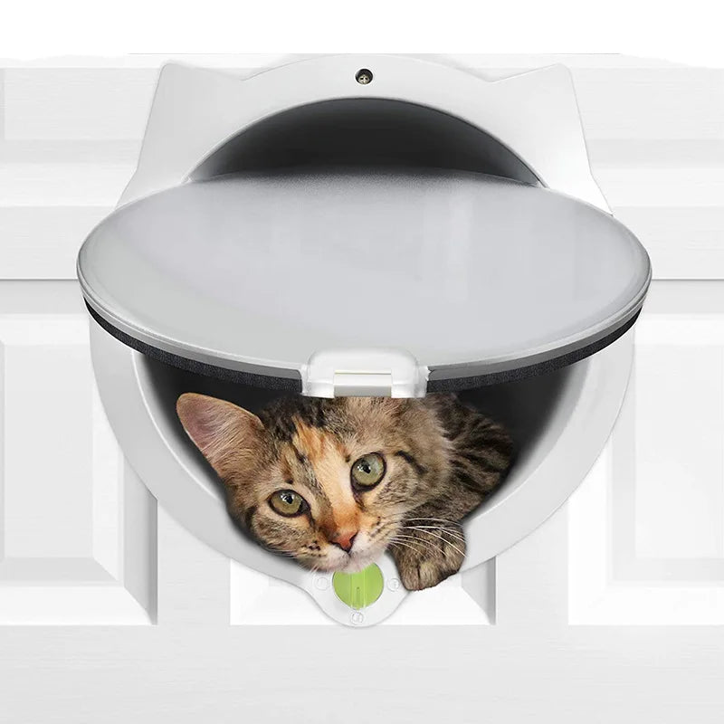 A gray cat is peering out of a white pet door flap, which is part of a larger white housing.