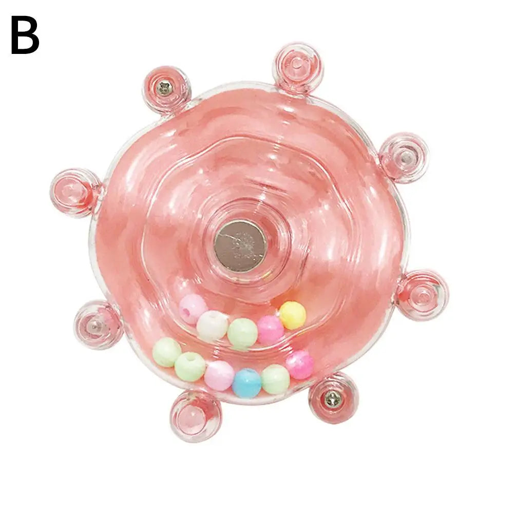 A pink rotating parrot treat dispenser with small colored candies at the bottom.