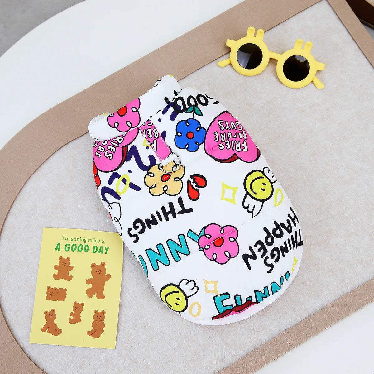 A white dog coat with colorful embroidery and yellow sunglasses resting on a beige surface.