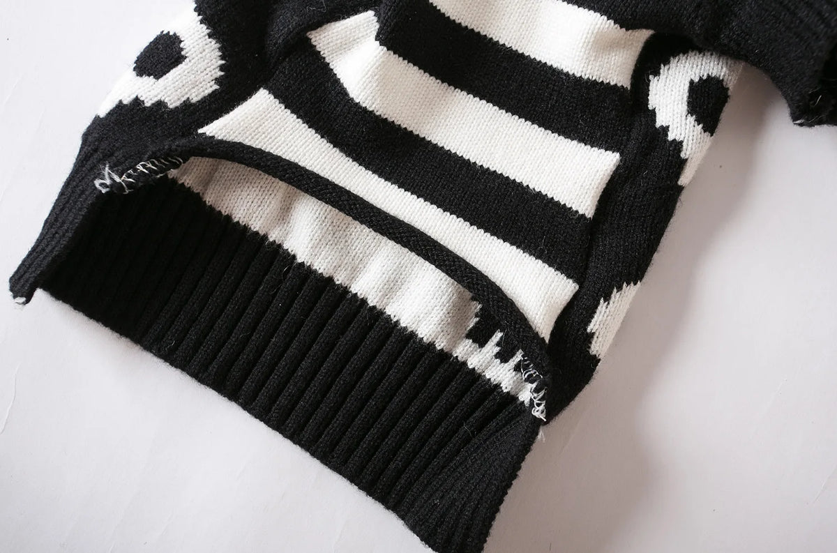 A close-up of a black and white striped knitted pet sweater for cats and small dogs.