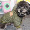 A small, fluffy dog wearing a olive green hooded winter jacket.