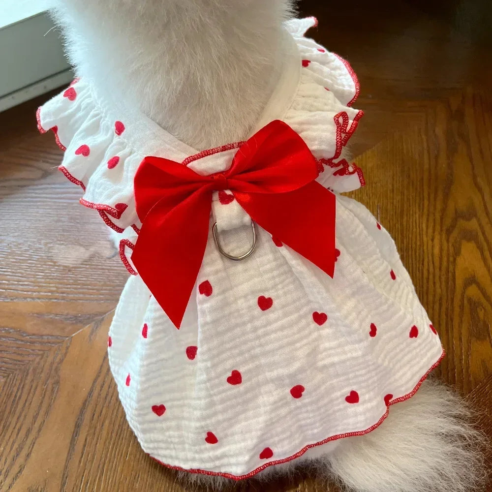 A white pet dress for a dog featuring red polka dots and a large red bow.
