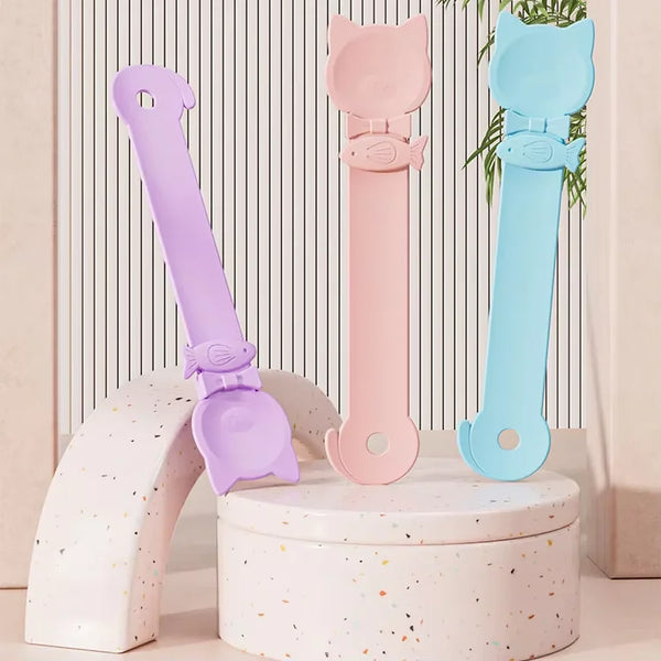 Tres cucharas para alimentador de gatos largas en púrpura, rosa y azul, expuestas en un soporte blanco.