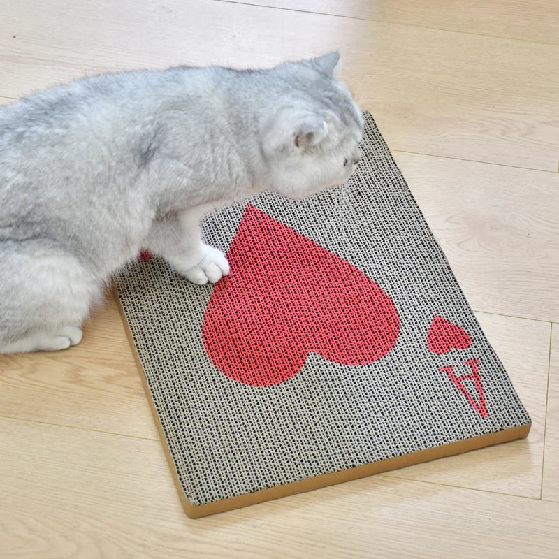 A gray cat is lying next to a vertical cat scratcher with a heart-shaped cutout on the surface.