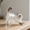 Figurine en verre clair d'un chat blanc assis sur une surface en bois.