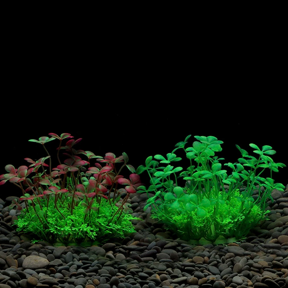 Exposition de plantes aquatiques artificielles avec du feuillage rouge et vert vif sur un substrat de gravier foncé.